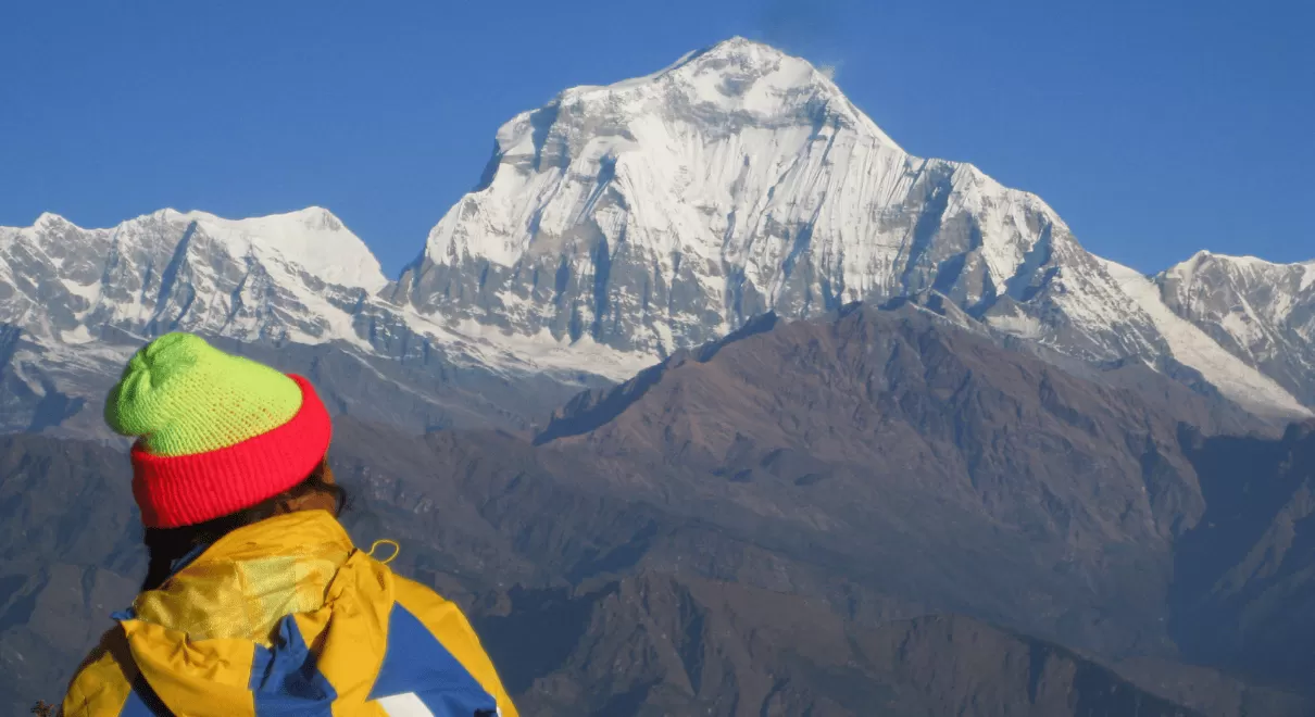 Solo female traveler trekking in Nepal Himalayas with mountain backdrop